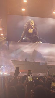 a large screen with a woman on it in front of a crowd at a concert