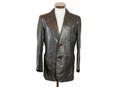 Size: 38 US/UK This 1970s brown leather jacket has a wide notch collar and lightly padded shoulders and closes in the front with two brown buttons. The European vintage blazer-style jacket has three pockets on the front, and features a contouring faux half-belt on the back. The jacket is lined in a brown satin viscose fabric, and has two inner pockets. Brand label: Priina (Made in Finland) Material: Genuine Leather Condition: Excellent (Professionally Cleaned ... soft and supple, with no stains, tears, wear spots, or weaknesses in the seams)  Chest = Best fit for 38 inches (96.52cm) Shoulder Width = 17 inches (43.18cm) Sleeve Length = 23 inches (58.42cm) Coat Length = 29 inches (73.66cm) Retro Single Breasted Leather Jacket For Work, Business Leather Jacket With Notch Lapel And Snap Buttons, Brown Blazer With Snap Buttons And Lapel Collar, Retro Single-breasted Leather Jacket For Work, Retro Business Blazer With Buttons, Vintage Outerwear With Snap Buttons For Office, Retro Blazer With Buttons For Business, Retro Business Blazer With Lapel Collar, Retro Blazer With Lapel Collar For Business