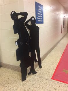 two mannequins dressed in black standing next to each other near a red carpet