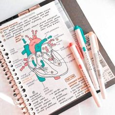 two pens are sitting on top of a notebook with an illustration of a heart and the inside of it