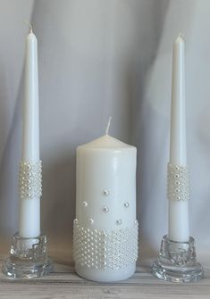 three white candles sitting next to each other