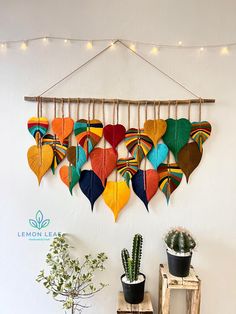 a group of colorful leaves hanging on a wall next to a potted plant and wooden ladder