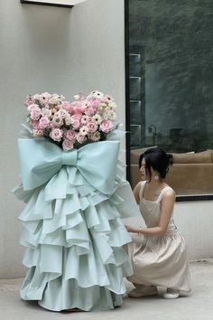 a woman kneeling down next to a giant flower arrangement