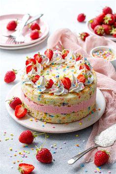 a cake on a plate with strawberries and sprinkles next to it