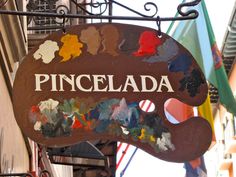 a sign that says pincelada hanging from the side of a building