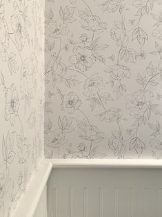 a white toilet sitting next to a wall with flowers on it