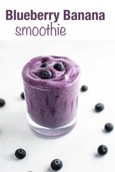 blueberry smoothie in a small glass with fresh blueberries scattered around it on a white surface