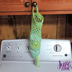 a green mesh bag hanging from the side of a washing machine