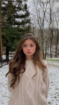 a woman standing in the snow wearing a sweater