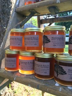 several jars of honey sit on a wooden shelf