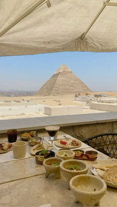 an outdoor table with food and drinks on it in front of the great pyramids