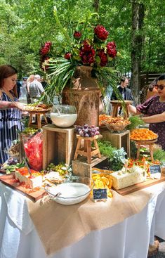 people are standing around a table with many different types of food and drinks on it