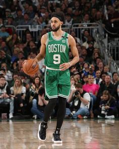 boston basketball player dribbling the ball in front of an arena full of people