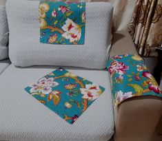 a couch with two matching pillows on it and one has a flowered pillow in the middle