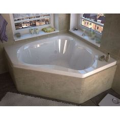 a bathroom with a large jacuzzi tub next to two windows and a rug on the floor