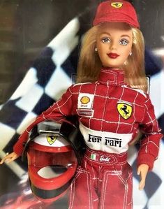 the doll is wearing a red racing suit and holding a helmet with both hands while standing on a checkered background