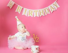 a baby in a pink tutu with a birthday cake