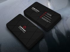 two black business cards sitting on top of a gray surface with red and white logos