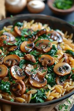 a pan filled with pasta and mushrooms on top of a wooden cutting board next to vegetables