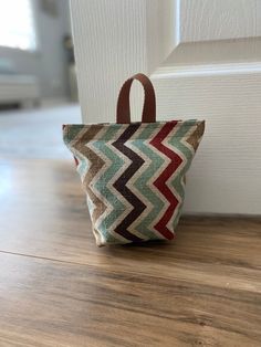 a small bag sitting on top of a wooden floor next to a white door with a brown handle