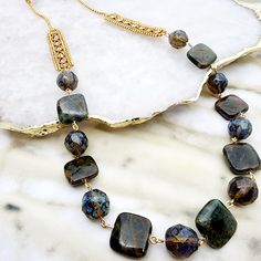 This elegant necklace exudes sophistication with its harmonious fusion of rustic charm and refined glamour. It features an array of multifaceted deep blue gemstones, lapis lazuli, with each stone's unique cut catching light from different angles to showcase their enigmatic hues. The stones are linked by delicate golden connectors that cascade into an opulent golden chain, intricately woven with a detailed design that adds an extra layer of richness to the piece. This necklace is a versatile acce Elegant Labradorite Beaded Necklaces, Elegant Blue Beaded Necklace With Gemstone Accents, Elegant Blue Beaded Necklaces With Gemstone Accents, Bohemian Sapphire Necklaces With Natural Stones, Elegant Jewelry With Faceted Labradorite Beads, Elegant Labradorite Necklace With Faceted Beads, Bohemian Jewelry With Rectangular Gemstone, Bohemian Rectangular Gemstone Jewelry, Lapis Lazuli Stone Jewelry For Healing