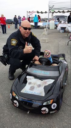 a police officer giving thumbs up next to a toy car