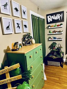 a green dresser in a room with pictures on the wall and dinosaur decorations above it