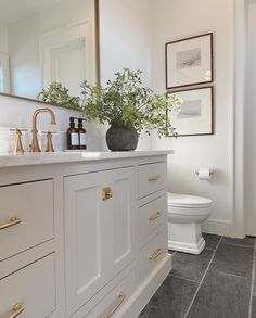 a bathroom with white cabinets and gold handles