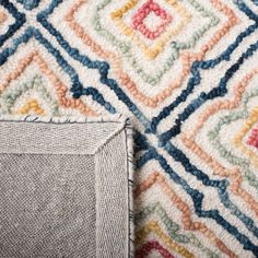 an area rug with different colored designs on it and a small piece of fabric next to it