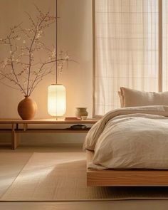 a bed with white linens and pillows in a room next to a vase with flowers