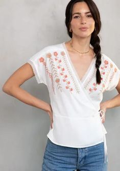 Delicate bohemian details add a pretty touch to this ultra-flattering wrap top. Featuring a wrap front, side tie closure, and lace trim. A simple and sophisticated style with embroidered detail. We love to style this warm-weather top with denim and a lace-up sandal. Chic White Wrap Top, White Tie Waist Top For Vacation, Spring White Blouse With Tie Waist, Bohemian Wrap Top For Day Out, Summer Embroidered V-neck Top With Lace Trim, Spring White Wrap Top, White Wrap Top For Spring, Feminine V-neck Embroidered Summer Top, Spring Vacation Wrap Top