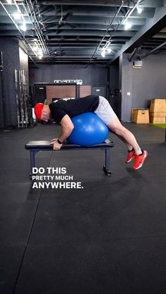 a man laying on top of a blue ball while holding his leg in the air