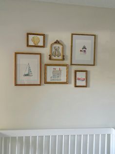 a white crib with framed pictures on the wall and a baby's bed