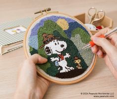 someone is working on a cross - stitch project with a snoopy dog in the woods