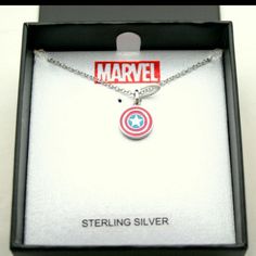 the captain america necklace is on display in a black box with silver lettering and a red, white, and blue logo