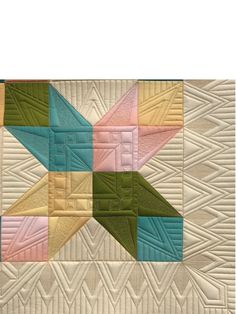 a quilted wall hanging with multicolored stars on it's sides and an arrow in the middle