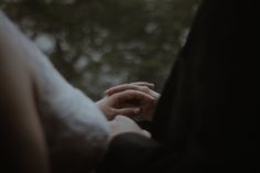 two people holding hands with trees in the background