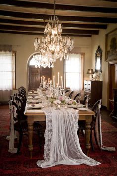 the dining room table is set with an elegant chandelier and white cloth draped over it