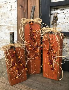 three wooden pumpkins decorated with berries and twine on top of a wood floor