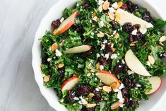 a salad with apples, raisins and nuts in a white bowl