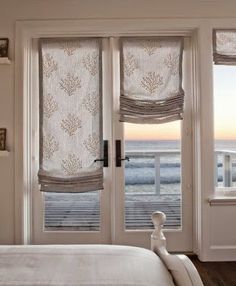 the bedroom has two windows with roman shades on them