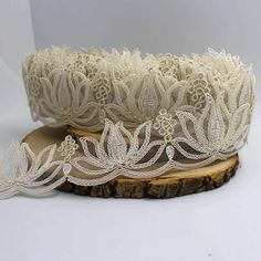 two rolls of white lace sitting on top of a piece of wood with an intricate design