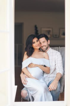 a man and woman are sitting on a couch together, one is hugging the other