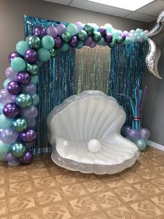 an under the sea themed balloon arch with seashells, balloons and streamers