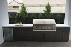 an outdoor kitchen with stainless steel appliances and grilling area in the middle of it