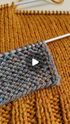 a close up of a knitted object with a needle in the middle and an image of a knitting stitch