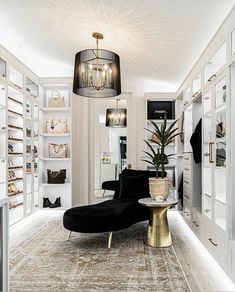 a room filled with lots of white shelves and furniture next to a black chair on top of a rug