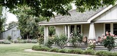 a woman sitting on the front porch of a house with flowers in the window boxes