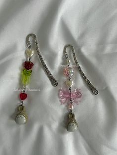 two earrings with charms attached to them on a white sheet