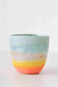 a ceramic bowl with multicolored stripes on it sitting on a white countertop